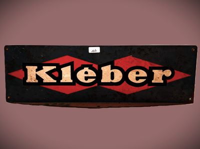Une vieille enseigne portant l'inscription « Kleber » est accrochée à un mur.