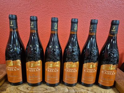 six bottles of wine sit on a table in front of a red wall
