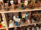 une étagère en bois sur laquelle sont disposées de nombreuses pièces de poterie de styles variés