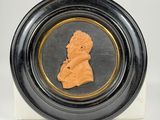 a close up of a black and gold plate with a bust of a man