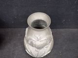 a silver vase sitting on a black surface next to a black vase