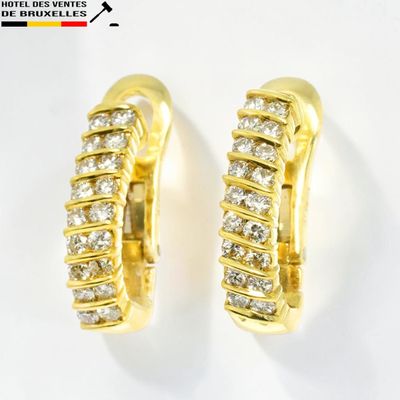 une paire de boucles d'oreilles créoles en or jaune et diamants sur fond blanc