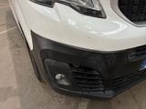 the front end of a white van parked in a parking lot