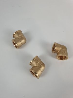 trois raccords de tuyauterie en laiton sur une surface blanche