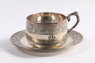 une tasse et une soucoupe en argent posées sur une soucoupe