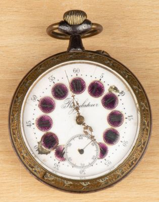 a pocket watch on a wooden table with a clock face