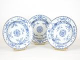 trois assiettes bleues et blanches à bordure dorée sur fond blanc