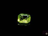 a green diamond on a black surface with a black background
