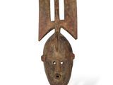 une sculpture en bois représentant une tête d'homme posée sur un socle noir