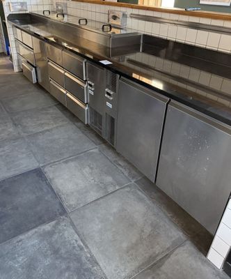 une cuisine équipée de plans de travail en inox et d'un réfrigérateur en inox