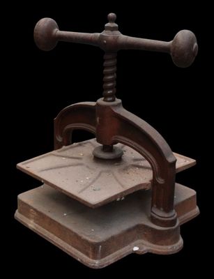 an old cast iron press with a wooden base on a black background