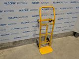 a yellow hand truck that is sitting in front of a wall