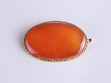 une image représentant un pendentif ovale de couleur orange entouré d'une corde
