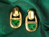 une paire de boucles d'oreilles vertes et dorées posées sur un tissu vert