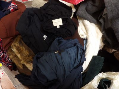 a pile of clothes on a bed with a teddy bear