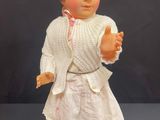 a doll that is wearing a white dress and a sweater