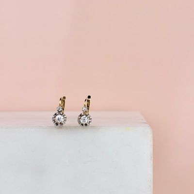 a pair of diamond stud earrings sitting on top of a white marble block