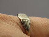 une bague en or ornée d'une pièce, au doigt d'une personne