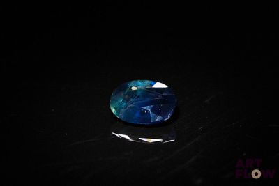 a close up of a blue and white stone on a black surface
