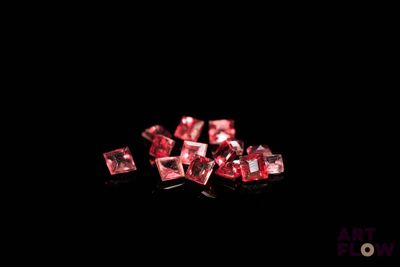 quelques diamants roses sur une surface noire, avec un fond noir