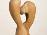 wooden sculpture of a man and a woman kissing on a white pedestal