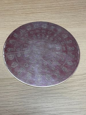 a silver plate with a design on it on a wooden table