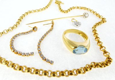 a necklace, ring, pin, and other jewelry on a white surface
