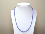 collier de perles violettes sur un mannequin blanc orné d'une perle bleue