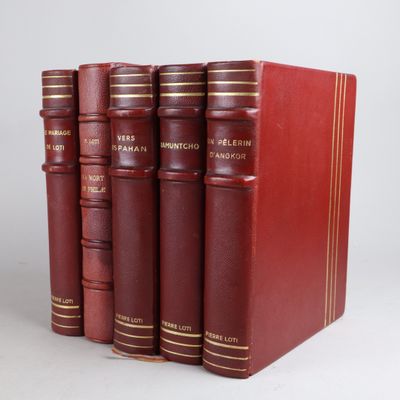 trois livres rouges superposés sur une surface blanche