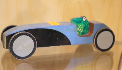 une petite voiture avec une grenouille posée dessus, posée sur une table