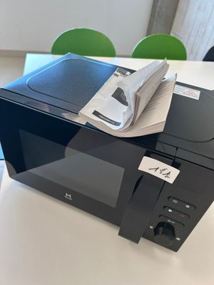 un micro-ondes posé sur une table, avec un livre dessus