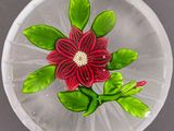 une assiette en verre ornée d'une fleur, posée sur une table