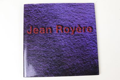 un gros plan sur un livre violet sur lequel figure le nom « Jean Royère »