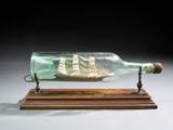 une bouteille en verre contenant un bateau, posée sur un socle en bois