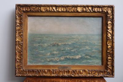 une peinture à l'huile représentant un bateau en mer, posée sur une table en bois