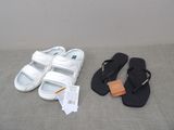 une paire de sandales blanches et une paire de sandales noires, l'une à côté de l'autre