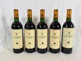 quatre bouteilles de vin rouge sont alignées sur une table
