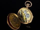 a gold pocket watch sitting on a black surface