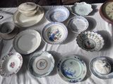 de nombreuses assiettes et bols posés sur une table, avec une horloge en arrière-plan