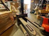 un chariot élévateur dans un entrepôt rempli de palettes et de cartons