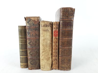 several old books are stacked on top of each other on a white surface