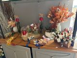 many vases of flowers on the counter in this room