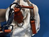 a white purse with a brown strap on it