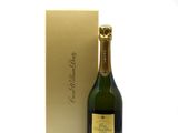 the bottle of champagne is next to a gold box on a white surface