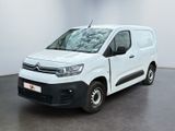 La camionnette blanche est garée dans une grande pièce au sol noir.