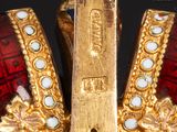 a close up of a gold and red crown with pearls on it