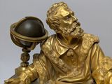 a gold statue of a man holding a globe and a book
