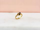 une bague en or sertie d'un diamant noir, posée sur une dalle de marbre