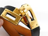 someone is holding a black and gold belt with a gold buckle