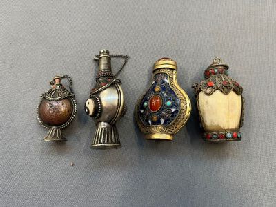 Quatre vases en argent de styles différents sont alignés sur une surface grise